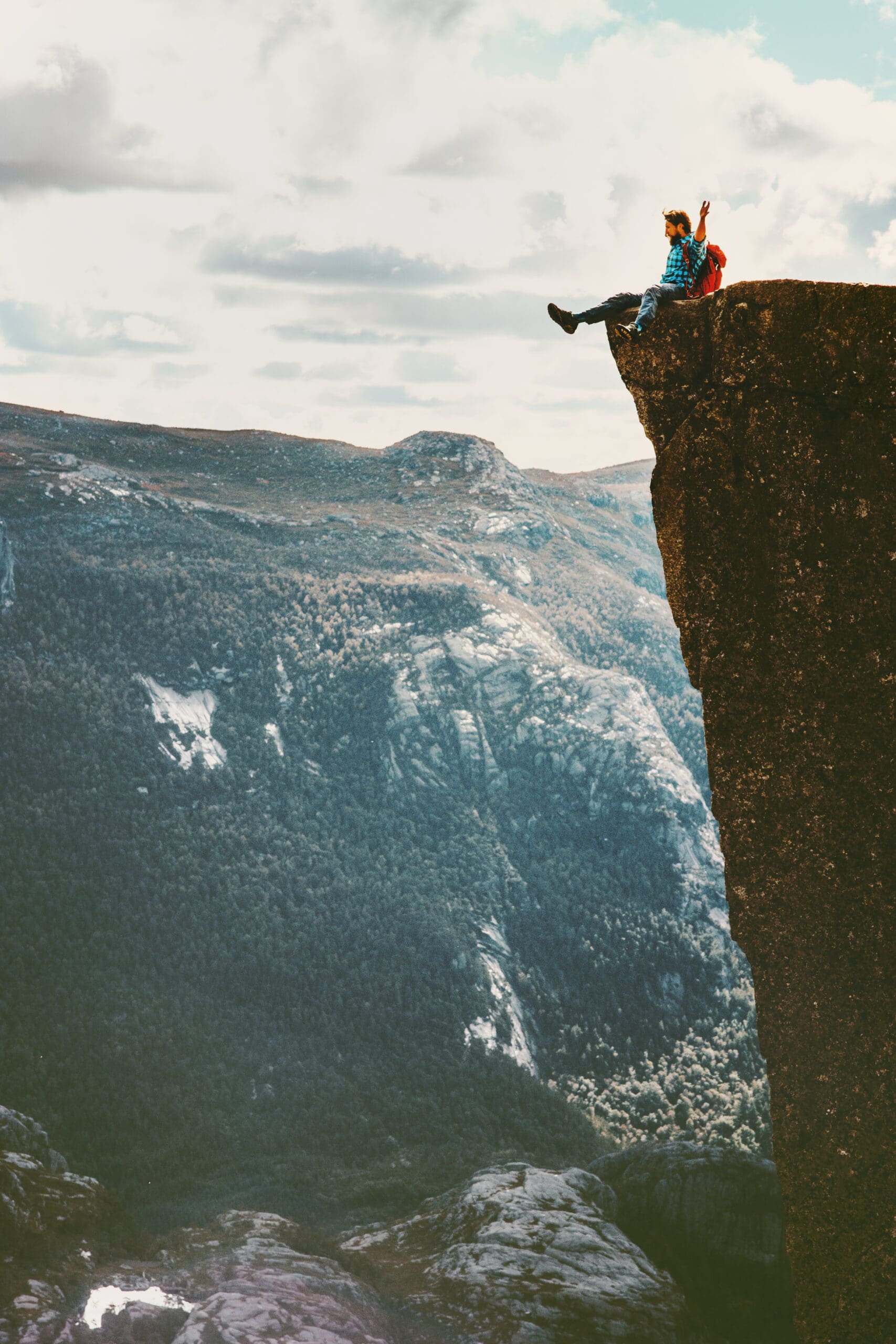 Man tourist sitting on Preikestolen cliff edge in Norway mountains Travel Lifestyle adventure concept extreme vacations outdoor Pulpit Rock